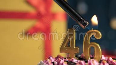 生日蛋糕46支金色蜡烛用打火机点燃，蓝色背景礼品黄色盒子用红丝带绑好